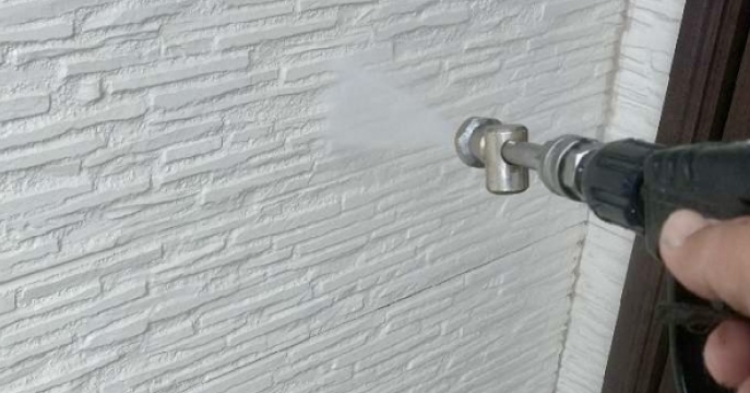 高圧洗浄機を使って外壁を洗浄している様子