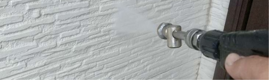 高圧洗浄機を使って外壁を洗浄している様子